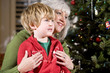 Boy sitting on grandmother's lap by Christmas tree