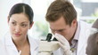 focused chemists looking through microscope