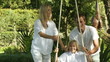 Happy Parents help their son on a swing