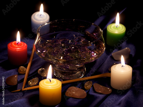 Photo: burning candles, cup with water, crystals, stones and two batons burning candles, cup with water, crystals, stones and two batons