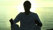 Man practising Yoga by the ocean