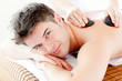 Handsome man receiving a back massage with hot stone Handsome man receiving a back massage with hot stone