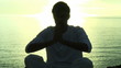 man doing yoga on the beach