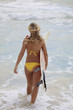 blond girl in a yellow bikini with her surfboard