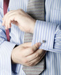 man in formal business attire adjusting cufflinks