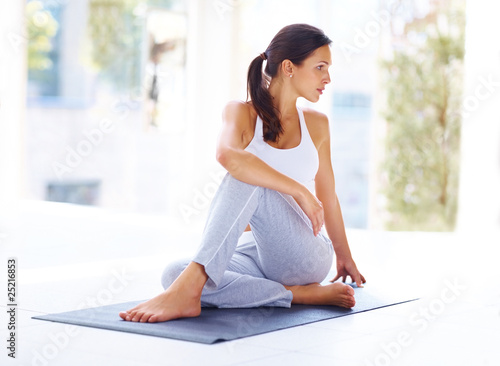Foto : Ardha Matsyendrasana - Young woman practising yoga exercise Ardha Matsyendrasana - Young woman practising yoga exercise