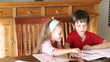 young brother and sister doing homeworks at home