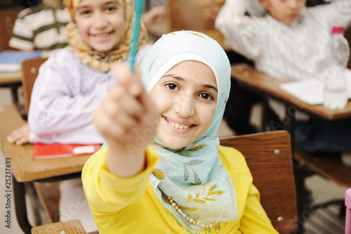 Photo: Adorable Muslim girl in classroom with her friends Adorable Muslim girl in classroom with her friends