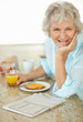 Happy senior woman having her breakfast at home