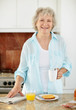 Happy mature woman with newspaper and having her breakfast
