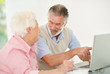Senior woman with a smiling mature man pointing at laptop