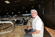 Senior man with laptop in barn Senior man with laptop in barn