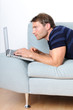 Young man relaxing with laptop on a couch