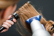 Hairdresser using hairbrush and hair-dryer