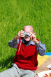 Alter Mann beim Fotografieren auf grüner Wiese - Hochformat