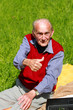 Alter Mann beim Fotografieren auf grüner Wiese - Hochformat