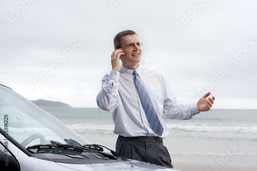 Foto: Lächelnder Geschäftsmann mit Handy am Strand Lächelnder Geschäftsmann mit Handy am Strand