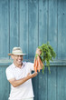 Photo: germany, bavaria, man in front of barn door holding bunch of carrots, smiling, portrait germany, bavaria, man in front of barn door holding bunch of carrots, smiling, portrait