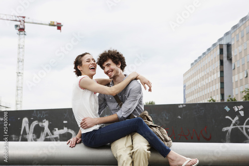 Photo: germany, berlin, young couple in front of new building, cranes in background germany, berlin, young couple in front of new building, cranes in background