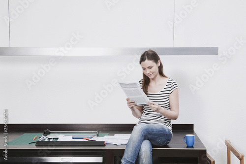 Photo: Frau sitzen auf dem Schreibtisch lesen Dokument Frau sitzen auf dem Schreibtisch lesen Dokument