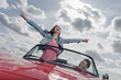 germany, berlin, couple in cabriolet, woman with arms outstretched
