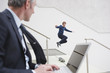 germany, hamburg, businesman using laptop, man in background skateboarding
