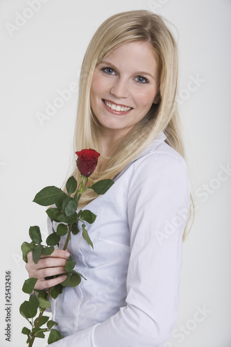 Photo: young woman holding a rose, smiling, portrait young woman holding a rose, smiling, portrait