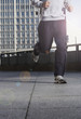 germany, berlin, person jogging on street, skyscrapers in background, low section