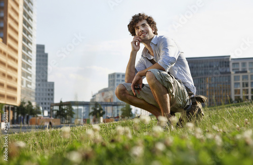 Photo: germany, berlin, young man using mobile phone, smiling, portrait germany, berlin, young man using mobile phone, smiling, portrait