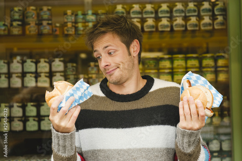 Photo: germany, bavaria, munich, viktualienmarkt, man in front of market stall holding bread rolls, portrait germany, bavaria, munich, viktualienmarkt, man in front of market stall holding bread rolls, portrait