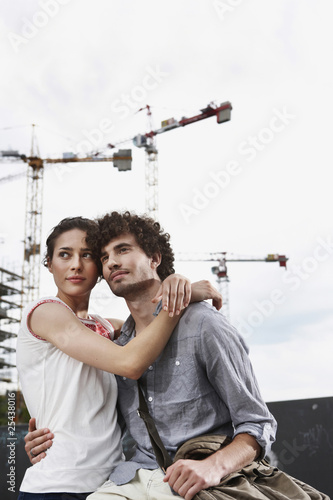 Photo: germany, berlin, young couple in front of new building, cranes in background germany, berlin, young couple in front of new building, cranes in background