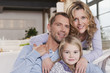 germany, cologne, family sitting on sofa, smiling, portrait, close-up