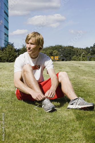 Foto: germany, berlin, young man tying shoe germany, berlin, young man tying shoe