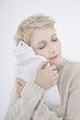 woman holding hot water bottle, eyes closed