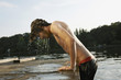 germany, berlin, young man climbing on jetty, side view