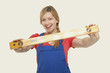 young woman holding spirit level, smiling, portrait
