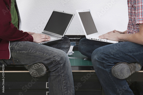 Photo: men sitting on desk using laptop. men sitting on desk using laptop.