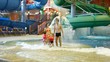 Charming woman, man and children near fountain in water park Charming woman, man and children near fountain in water park