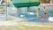 Charming woman, man and girl in life jacket in indoor water park Charming woman, man and girl in life jacket in indoor water park