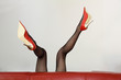 Sexy Frau in roten High-Heels liegt auf dem Sofa