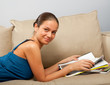 Young female lying on the sofa with magazines in hands