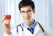 Happy smiling doctor with apple, at office
