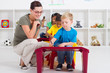 happy teacher helping kindergarten students draw