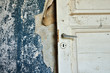 Torn wallpaper and wooden door in abandoned house.