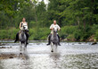 Ein Mann und eine Frau reiten durch eine Fluss