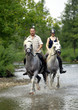 Ein Mann und eine Frau reiten durch eine Fluss