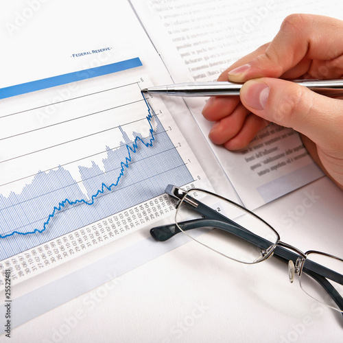 Foto: Businessman's hand showing diagram on financial report with pen. Businessman's hand showing diagram on financial report with pen.