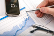 Businessman's hand showing diagram on financial report with pen.