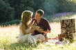 A young couple sitting on the grass, having a picnic