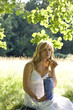 A young woman sitting on the grass, eating crisps